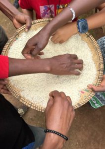 Close-up of hands shifting rice together during a cultural cooking class in Moshi
