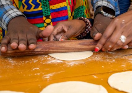 Guests preparing Tanzanian dishes during a hands-on cooking class at Lifted Strong NGO in Arusha